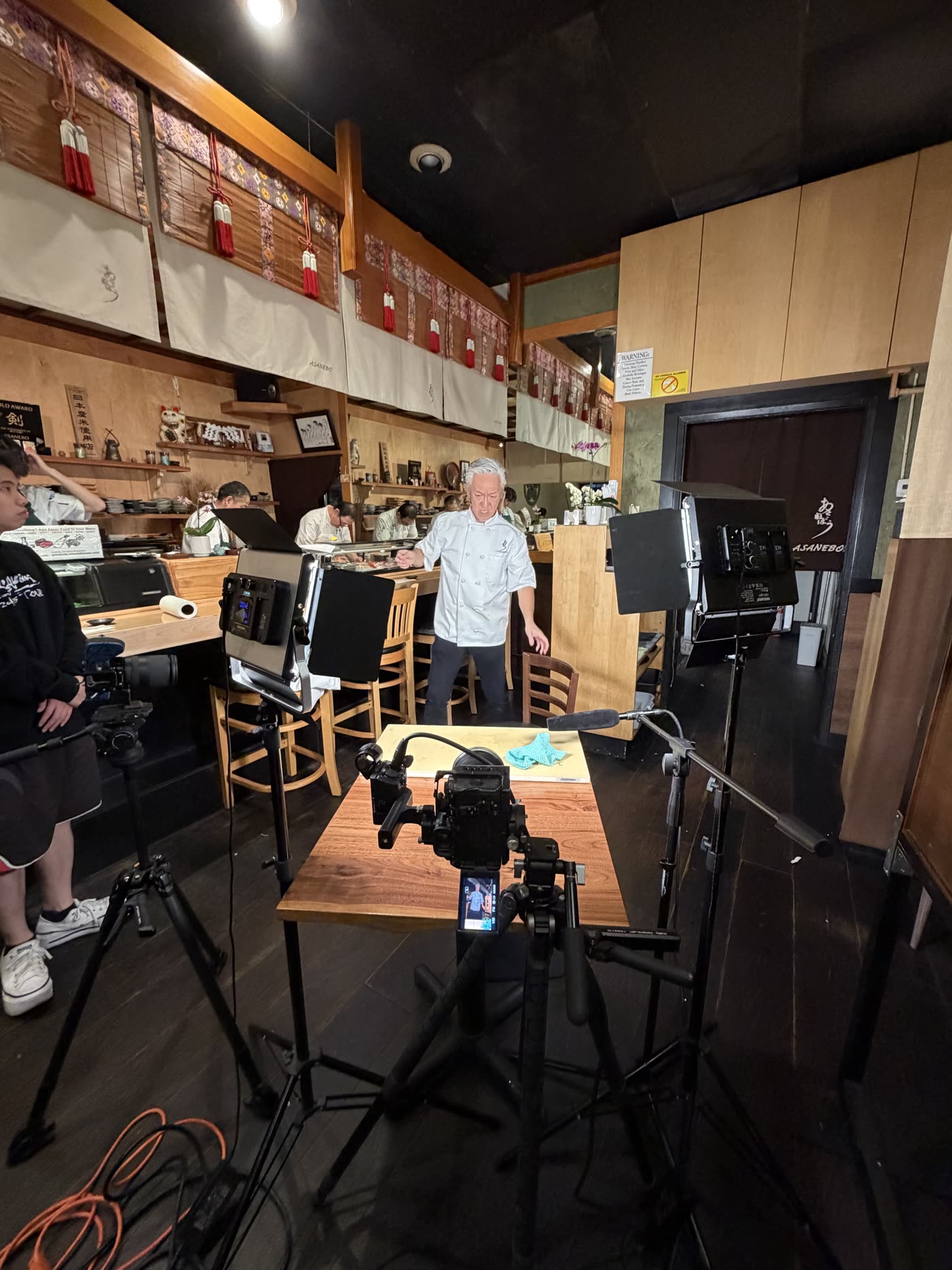 On set at Asanebo — full production rig around the sushi counter
